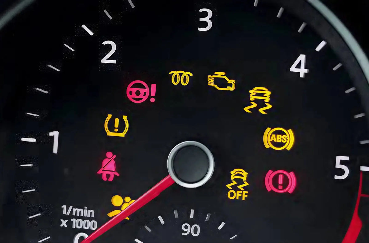 Muestra la brillante pantalla del cuadro de instrumentos digital de un coche moderno iluminada de noche, completamente llena de varios testigos de advertencia amarillos y rojos.