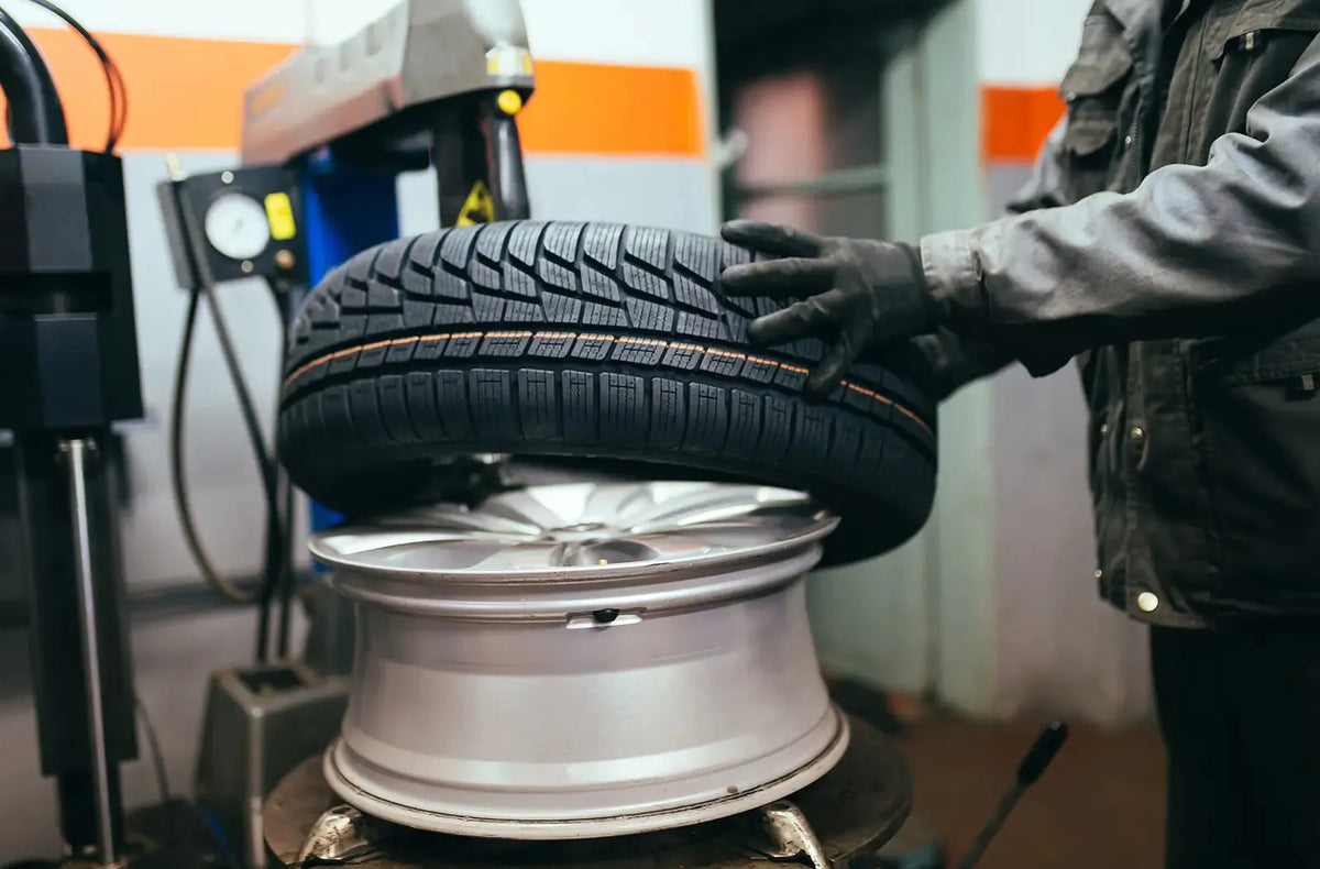 Primer plano del cuadro de instrumentos de un coche, destacando el testigo ámbar iluminado de advertencia de presión de neumáticos (TPMS) con el signo de exclamación.