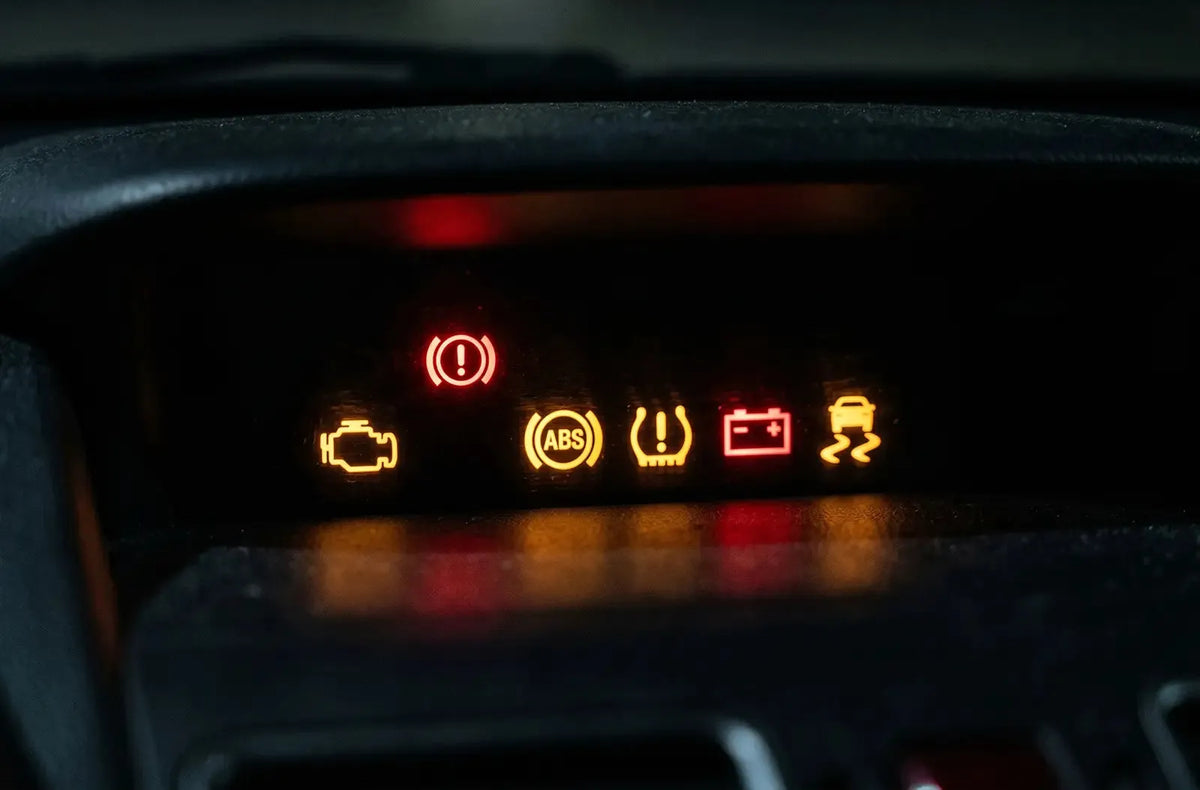 Muestra el cuadro de instrumentos digital de un vehículo de noche con múltiples testigos amarillos y rojos encendidos a la vez, incluidos los de fallo de motor, ABS y batería.