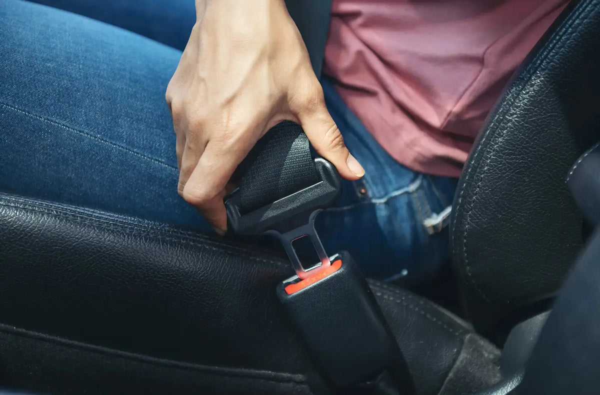 Primer plano del pilar B interior de un coche, mostrando la correa negra del cinturón de seguridad pasando directamente a través del conjunto de la guía mecánica de plástico.