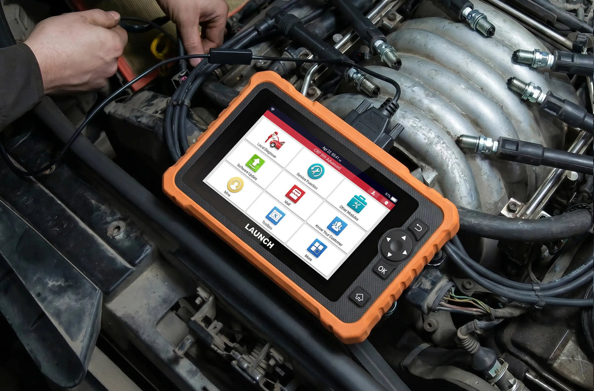 Un escáner LAUNCH CRP 919 Advanced sobre un motor abierto en mantenimiento. Con funda naranja resistente, pantalla táctil a color con menús y conectado por cable negro al vehículo.