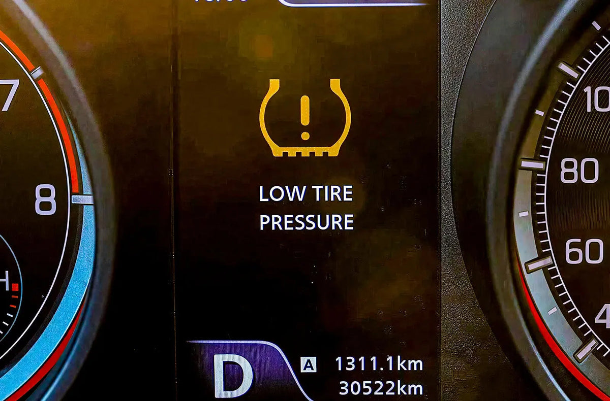 Primer plano del perfil de un neumático en llanta personalizada, destacando la válvula metálica con sensor de presión.