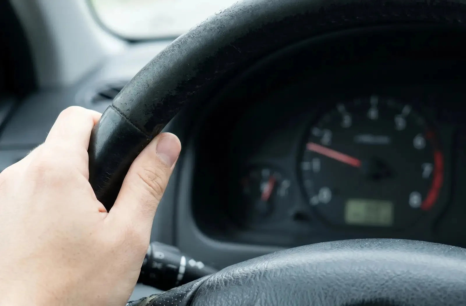 Primer plano del panel de instrumentos analógico de un coche, que muestra la aguja del tacómetro oscilando cerca de las bajas revoluciones (RPM).